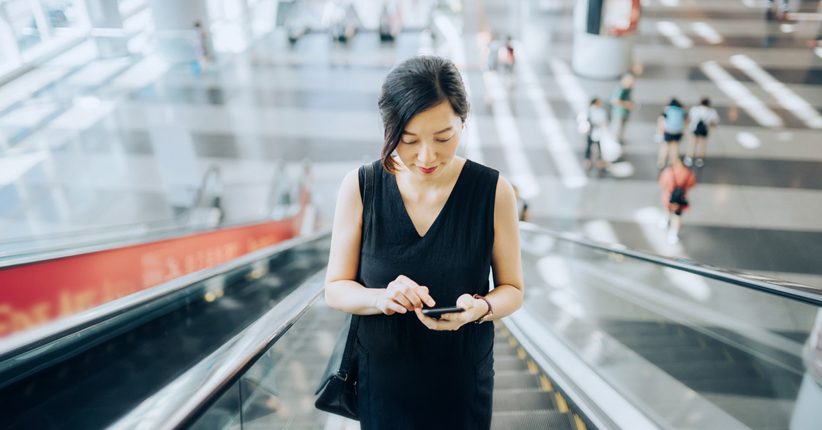 woman looking at phone on escalator