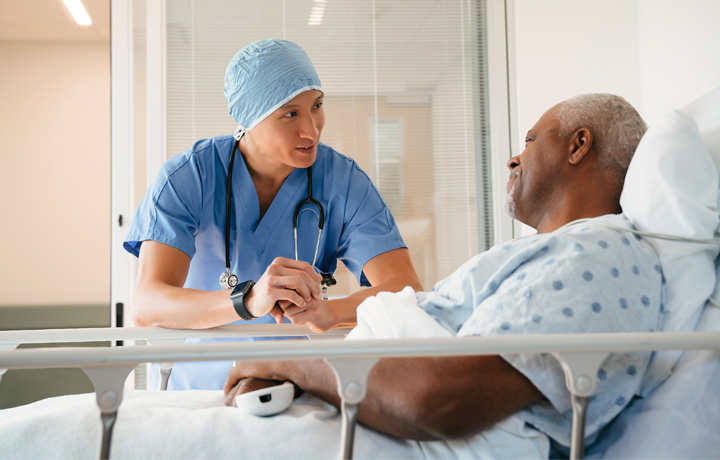 Surgeon talking with patient lying in hospital bed